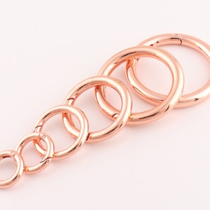 Op de afbeelding: Set van zes sleutelringen van roosgoudkleurig metaal in verschillende maten. De sleutelringen zijn allemaal open en hebben een gladde afwerking.