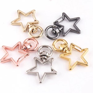 Puede incluir: Cuatro llaveros de metal en forma de estrella en diferentes acabados: dorado, dorado rosa, plateado y negro.