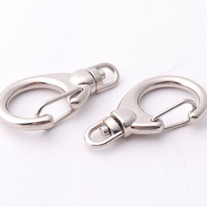 May include: Two silver swivel snap hooks with a spring-loaded gate. The hooks are designed for attaching to a keychain, bag, or other items.