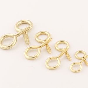 May include: Five gold-toned screw-in eyelet hooks of varying sizes. The hooks are made of metal and have a shiny finish.