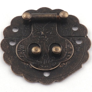May include: Antique brass-toned latch with a decorative floral design and two round knobs. The latch is designed to be used on a box, chest, or other small wooden object.