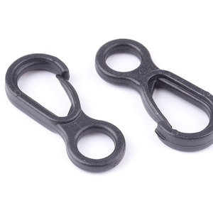 Puede incluir: Dos clips de gatillo de plástico negro con un bucle en un extremo y un mosquetón en el otro.