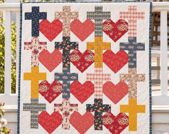 May include: A rectangular quilt featuring a repeating grid pattern of alternating fabric hearts and crosses. The hearts are various shades of red and pink, while the crosses display diverse floral and geometric prints in blue, yellow, and cream.