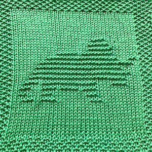 Può includere: Un canovaccio di maglia verde con un semplice disegno geometrico. Il disegno è una forma triangolare con una serie di linee che la attraversano.