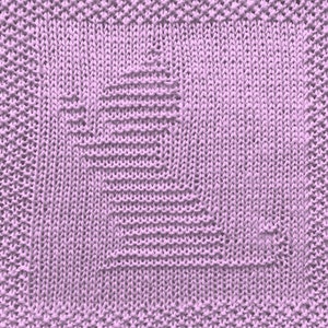 May include: A close-up of a knitted dishcloth in a light purple color. The dishcloth has a square shape and a textured pattern.