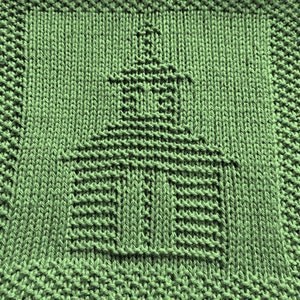 Könnte beinhalten: Ein grüner Strick-Geschirrtuch mit einem geometrischen Muster in der Mitte. Das Muster ähnelt einer Kirche oder einem Kirchturm.