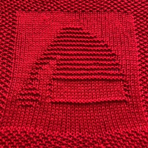 May include: Red knitted dishcloth with a square pattern in the center.