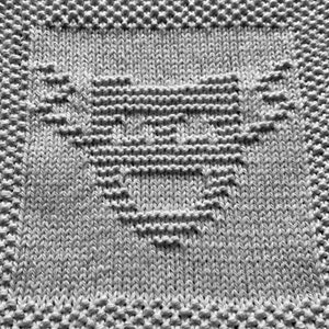 Puede incluir: Un paño de cocina de punto gris con un diseño en forma de corazón en el centro.