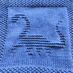 May include: A blue knitted dishcloth with a woven design of a bird in flight.