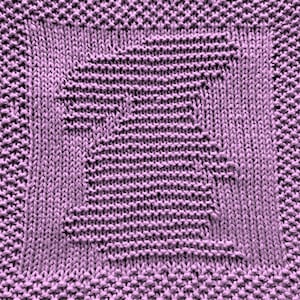 May include: A close-up of a purple knitted dishcloth with a square pattern.