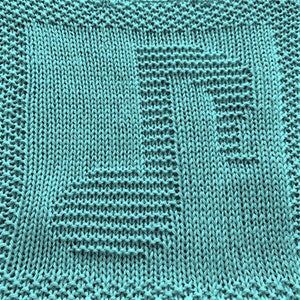 May include: A teal blue knitted dishcloth with a woven pattern.