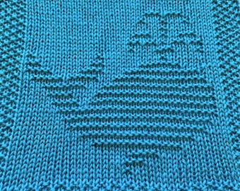 May include: A teal blue knitted dishcloth with a woven heart design.