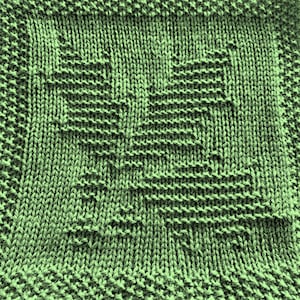 May include: A close-up of a green knitted fabric with a textured pattern. The fabric is made of yarn and has a soft, fuzzy texture.