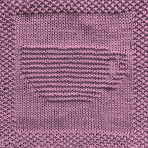 May include: A close-up of a knitted dishcloth in a light purple color. The dishcloth has a square shape with a smaller square in the center.