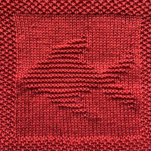 Könnte beinhalten: Roter Strickstoff mit geometrischem Muster. Der Stoff ist in einem engen, dichten Muster gewebt, wodurch eine strukturierte Oberfläche entsteht.