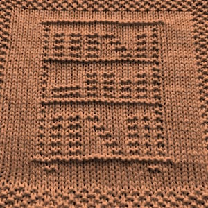 May include: A brown knitted dishcloth with a square pattern in the center.