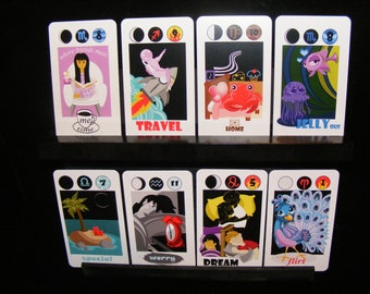 Puede incluir: Ocho cartas con símbolos astrológicos y números, cada una con una ilustración diferente y una palabra debajo. Las palabras son "me time", "travel", "home", "jelly out", "special", "worry", "dream", y "flirt".