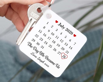 May include: White keychain with a calendar design featuring the month of July 2020 with a red heart highlighting the 28th. The text "The Day We Became Us" is written below the calendar with the signature "Love Steph xxx".