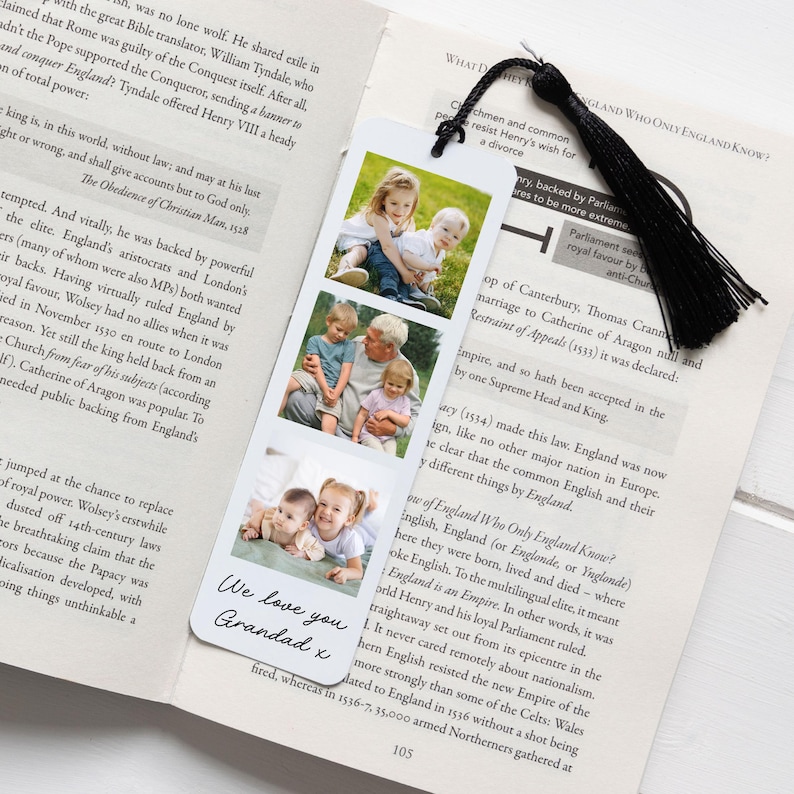 May include: A personalized bookmark featuring three family photos and a black tassel. The bookmark has the text "We love you Grandad x" in a handwritten style. The photos show a grandfather with his grandchildren.