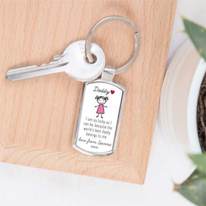 May include: Silver keychain with a rectangular tag that says "Daddy" and features a stick figure drawing of a girl in a pink dress. The tag also includes the text "I am as lucky as I can be, because the world's best daddy belongs to me love from Sienna xoxo".