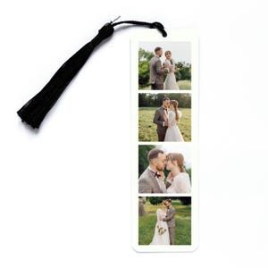 May include: A rectangular white bookmark featuring four stacked photographic prints of a couple in a field, accompanied by a black tassel attached to the top through a small hole. The images show the couple in various poses outdoors.