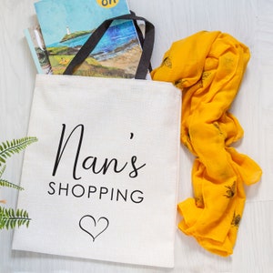 May include: White canvas tote bag with black handles and the text "Nan's Shopping" with a heart symbol.
