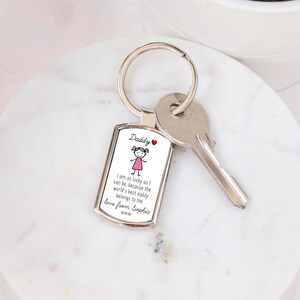 May include: Silver keychain with a white rectangular tag that says "Daddy" and features a cartoon girl in a pink dress. The tag also includes the text "I am as lucky as I can be, because the world's best daddy belongs to me love from Sophia xxx".