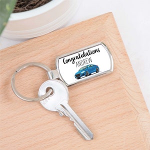 May include: Silver keychain with a blue car and the text "Congratulations Andrew" on a white background.