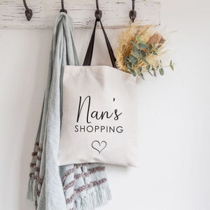 May include: A white tote bag with black handles and the text "Nan's Shopping" with a heart symbol.