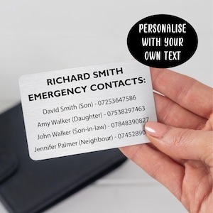 May include: A rectangular silver-toned metal card featuring black printed text that reads RICHARD SMITH EMERGENCY CONTACTS followed by a list of names and phone numbers. A black oval graphic in the corner contains the text PERSONALIZE WITH YOUR OWN TEXT.
