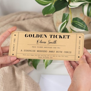 Puede incluir: Un "Golden Ticket" de madera con texto negro, sostenido por manos. El billete dice "Golden Ticket" y "Olivia Smith", prometiendo un fin de semana sorpresa. El texto tambi&eacute;n incluye la fecha y hora del viaje.