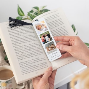 May include: A personalized bookmark featuring three family photos and the text "We love you Grandpa." The bookmark has a black tassel and is held open in a book. A mug is visible in the lower left corner.