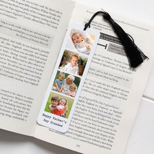 May include: A white bookmark with a black tassel, displaying four family photos and the text "Happy Father's Day Grandad." The bookmark is in an open book.
