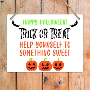 May include: A rectangular white sign with a jute rope hanger featuring the green text HAPPY HALLOWEEN!, black text TRICK OR TREAT, and orange text HELP YOURSELF TO SOMETHING SWEET. Two black bats and three orange jack-o'-lanterns are printed below.