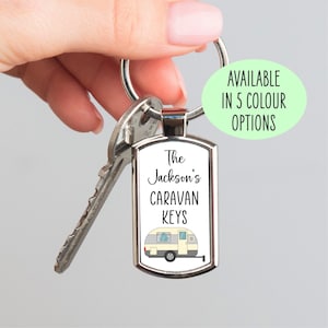 May include: A silver metal keychain with a white caravan illustration and the text "The Jackson's Caravan Keys".