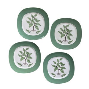 Puede incluir: Cuatro platos cuadrados con esquinas redondeadas. Cada plato tiene un centro blanco con un diseño de árbol verde y un borde verde. El árbol tiene hojas verdes y un tronco marrón. Los platos están dispuestos sobre un fondo blanco.