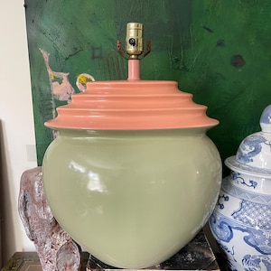 May include: A ceramic lamp base with a heart-shaped body in a light green color. The top of the lamp base is a layered, tiered design in a light pink color.