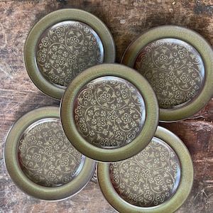 May include: Five green ceramic plates with a brown floral pattern. The plates have a raised rim and a glossy finish.
