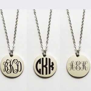 May include: Three silver necklaces with round pendants featuring different monogram initials. The pendants are engraved with the letters "BKD", "CKK", and "JEK".