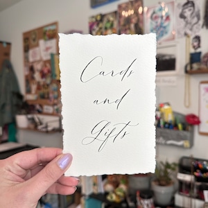 May include: A white card with the text "Cards and Gifts" written in black calligraphy.