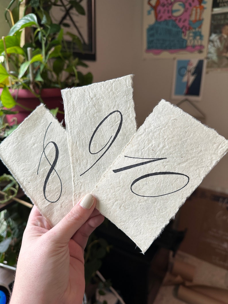 May include: Three white paper cards with black calligraphy numbers 8, 9, and 10.