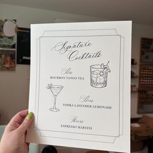May include: A white rectangular card with black text and line art illustrations. The header reads Signature Cocktails. It lists His Bourbon Tango Tea, Hers Vodka Lavender Lemonade, and Theirs Espresso Martini, accompanied by two cocktail glass drawings.