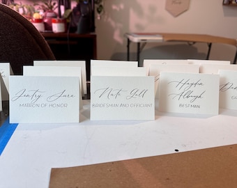 Tarjetas de lugar o tarjetas de acompañante rasgadas con pliegues de tienda para bodas y eventos, tarjetas de papel hechas a mano, números de mesa para tarjetas de acompañante con caligrafía de boda