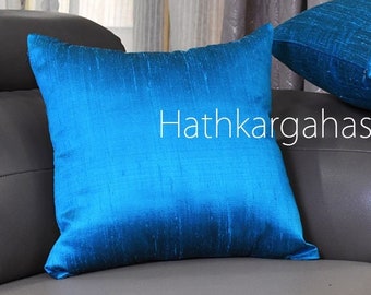 May include: Two turquoise blue silk pillow covers with a subtle sheen. The pillow covers are on a gray couch with the text "Hathkargahastore" printed on the couch.