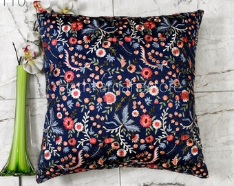 Op de afbeelding: Een donkerblauw kussen met een bloemenpatroon geborduurd in roze, wit en groen. Het kussen is vierkant en heeft een zachte, pluche textuur.