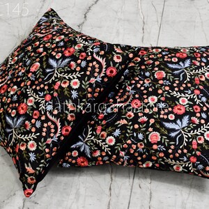 May include: Two black square throw pillows with a floral embroidery pattern in shades of pink, white, and blue. The pillows are made of a soft, luxurious fabric and are perfect for adding a touch of elegance to any room.