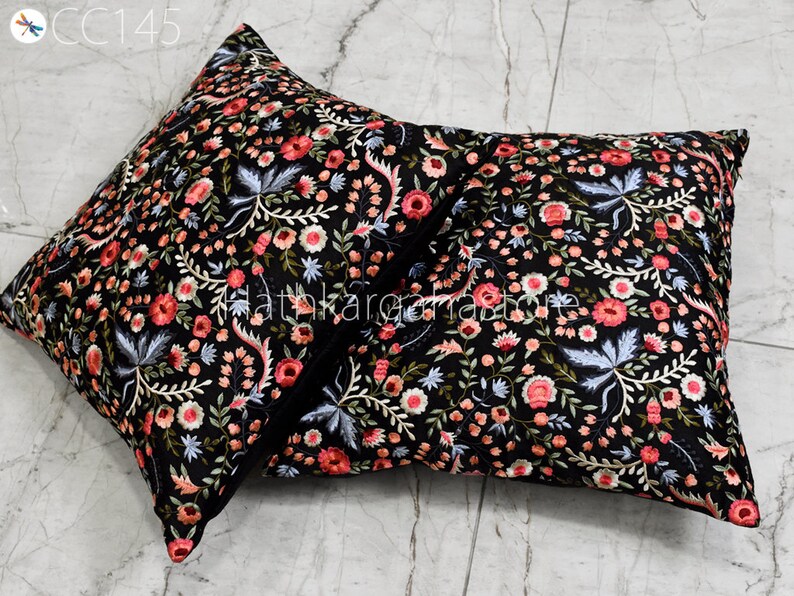 May include: Two black square throw pillows with a floral embroidery pattern in shades of pink, white, and blue. The pillows are made of a soft, luxurious fabric and are perfect for adding a touch of elegance to any room.