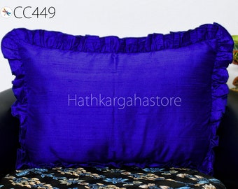 May include: A royal blue pillow with a ruffled edge. The pillow is made of a soft, silky fabric. The pillow is sitting on a black and white patterned surface. The text "Hathkargahastore" is visible in the center of the pillow.
