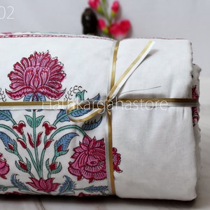 May include: A white cotton quilt with a floral print in shades of pink, blue, and green. The quilt is folded and tied with a gold ribbon. The text "DC02" is visible in the top left corner of the image.