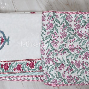 May include: A white cotton bed sheet with a pink and green floral print. The sheet has a red and white striped border and a single large floral design in the top left corner. The sheet is labeled "DC02".